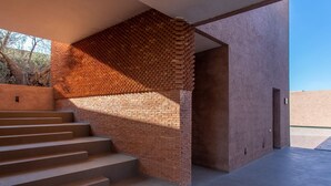 A modern building with a brick wall and a staircase leading to an entrance.