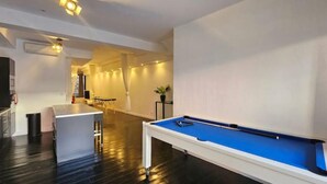 A modern room with a pool table, a small bar area, and a dining table.