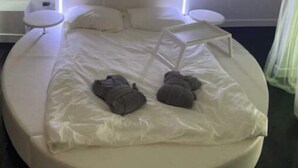 A modern hotel room with a large bed, white bedding, and bedside tables.