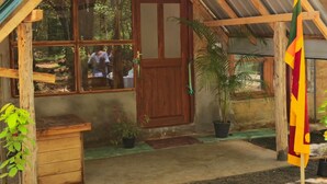 Une maison en bois avec un toit en métal, une porte en bois et une fenêtre.