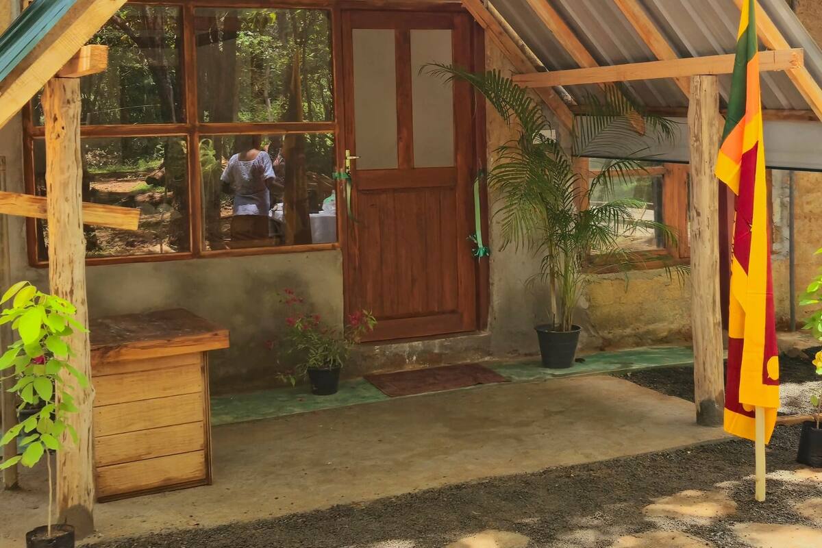 A wooden house with a metal roof, a wooden door, and a window.