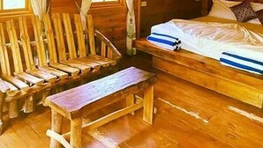 Une pièce dans un chalet en bois, comprenant un lit, un banc et une table.