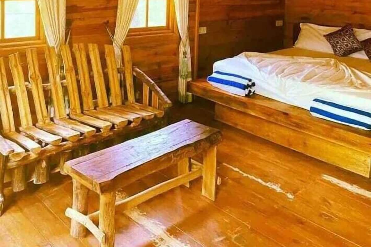 A wooden cabin room with a bed, a bench, and a table.