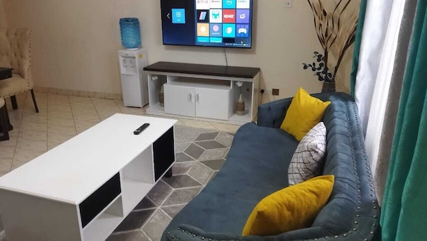 Un saló amb televisió de pantalla plana, un sofà, una taula de centre i un armari.