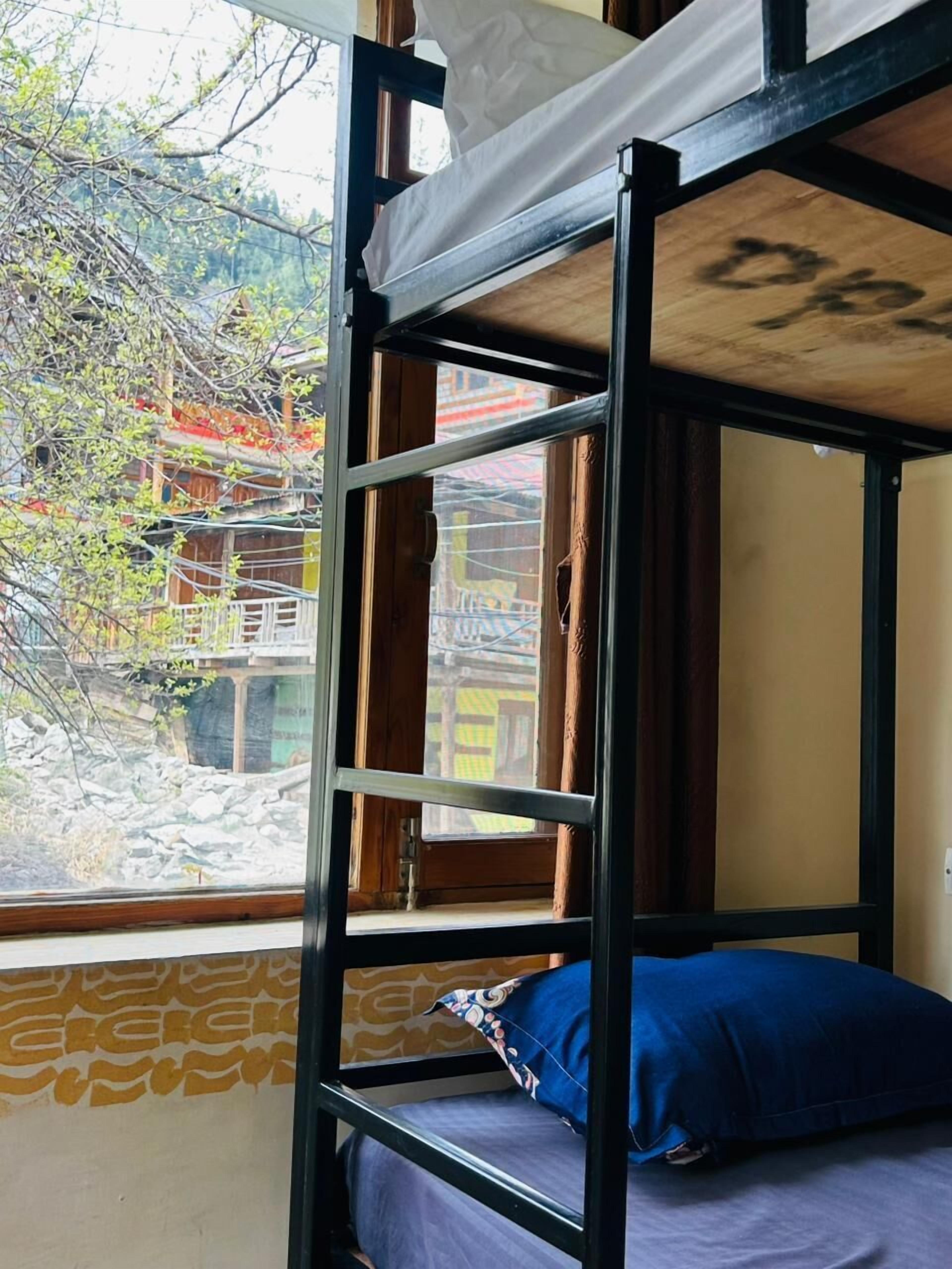 Una cama litera con una ventana, un cojín azul y una pared con diseño.