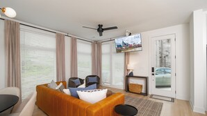 Una sala de estar moderna con un sofá, sillas, un televisor y una chimenea.