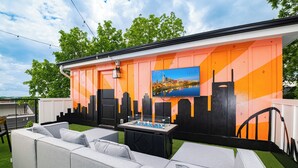Un área de estar al aire libre con un sofá y una mesa, un mural en la pared y una pintura de un paisaje urbano.