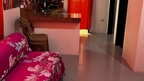 A compact room with a bed, a small kitchenette, and a door leading to another room. - Feel like home one bedroom studio 
full kitchen, Near Satisima Trinidad Church (Malolos)