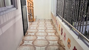 A corridor with patterned floor tiles, a metal railing on the right, and a door on the left. - Feel like home one bedroom studio 
full kitchen, Near Satisima Trinidad Church (Malolos)