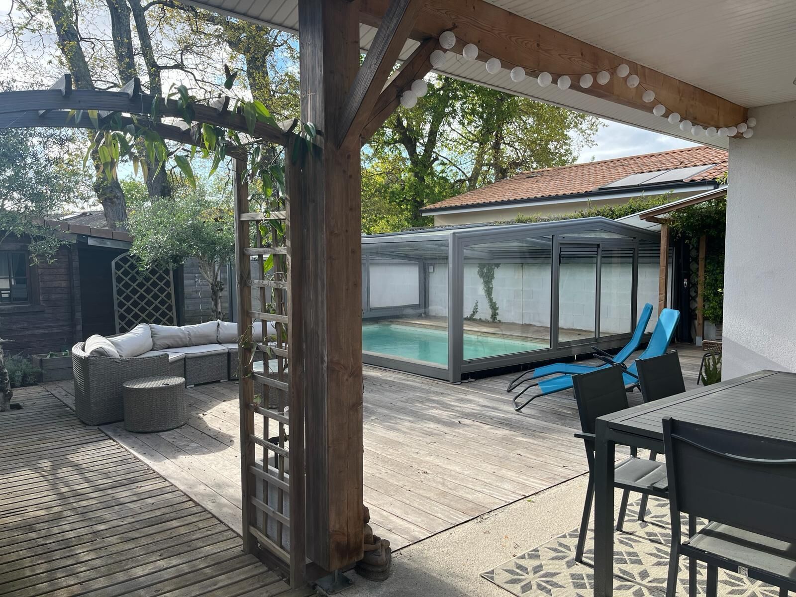 Área externa coberta com piscina, deck de madeira e área de estar.