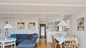 A modern living room with a blue sofa, white dining table, and wooden chairs. - "Hira" - 200m from the sea by Interhome (Egernsund)