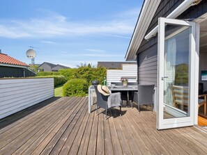 Una terraza con mobiliario exterior, una antena parabólica y una puerta de cristal que da a una habitación.