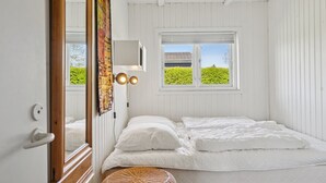 A bedroom with a bed, a window with a view of greenery, a wall-mounted lamp, and a mirror. - "Hira" - 200m from the sea by Interhome (Egernsund)