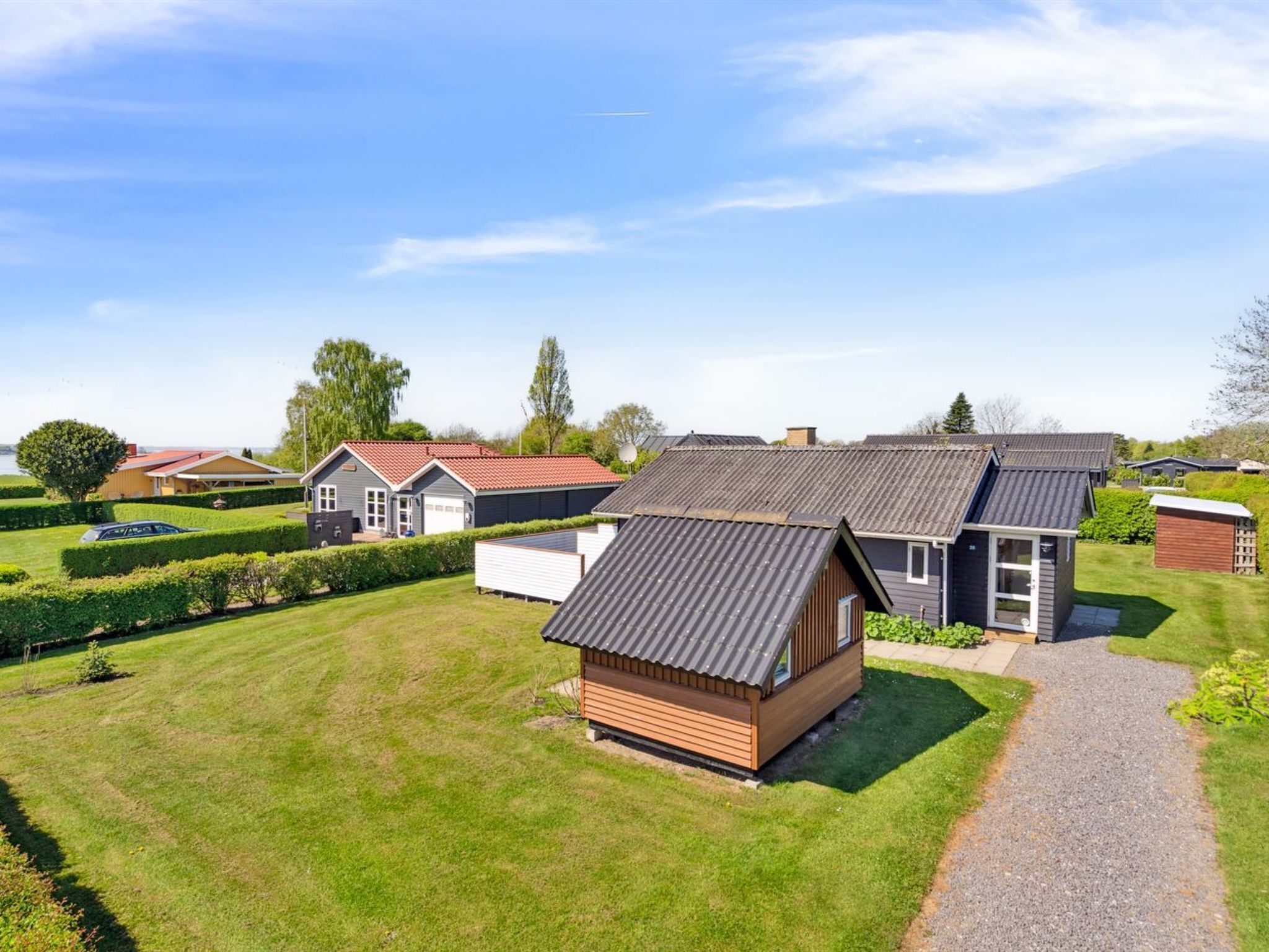A residential area with multiple houses, a well-maintained lawn, and a gravel path.