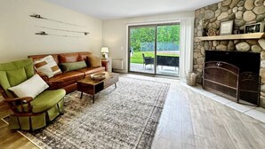 Un salon avec une cheminée, un fauteuil vert, un canapé et une table basse.
