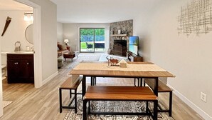 Un vaste espace de vie doté d’une grande table en bois, de bancs et d’une cheminée en pierre.