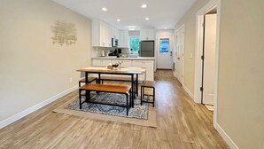 Une cuisine spacieuse avec un coin repas, des meubles blancs et un plancher en bois.
