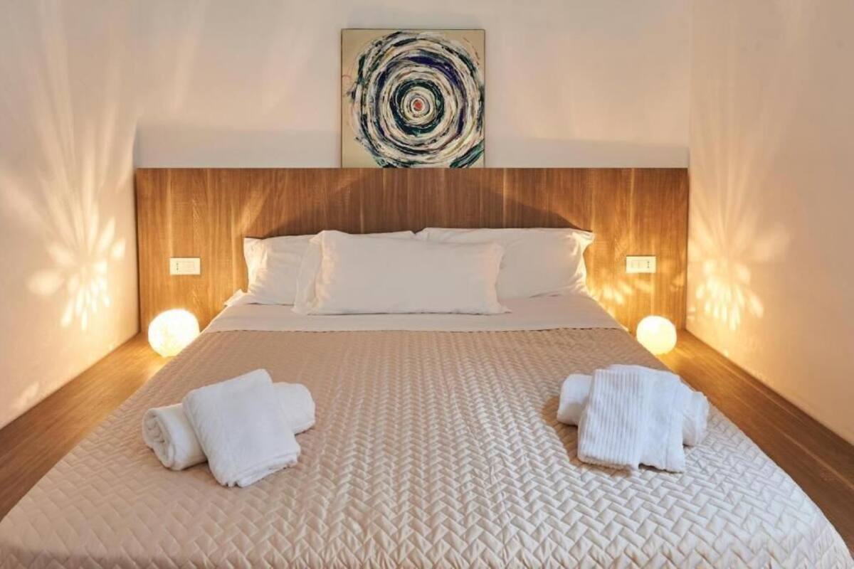 Una cama bien hecha con cubrecolcha acolchado, dos almohadas y dos toallas enrolladas sobre la cama.