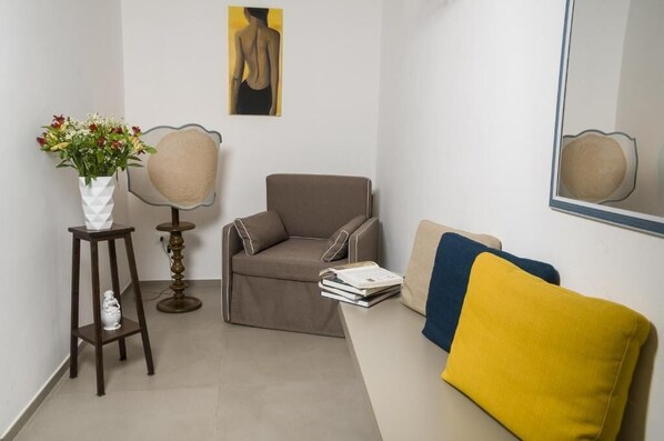 A modern room with a brown sofa, a yellow cushion, a white vase with flowers, and a framed artwork on the wall.