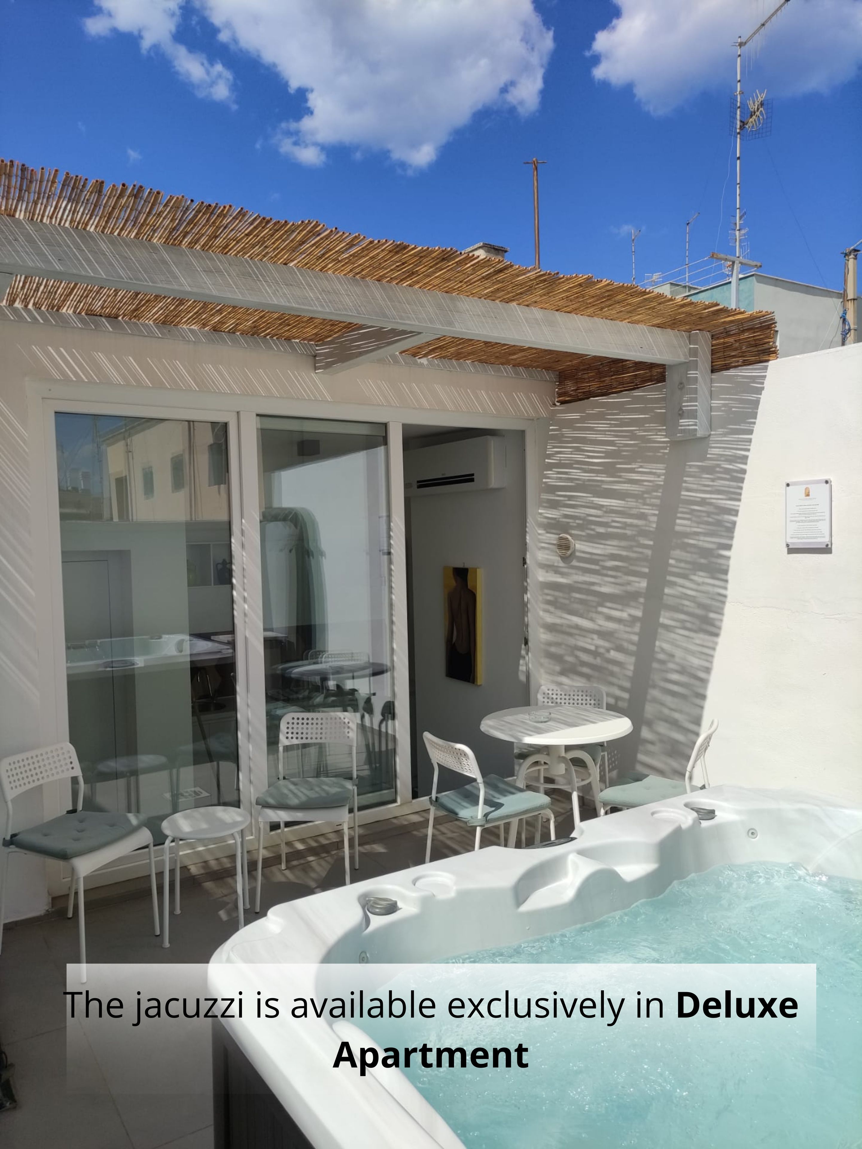 Un balcón con jacuzzi, puertas de vidrio y mobiliario de exterior.