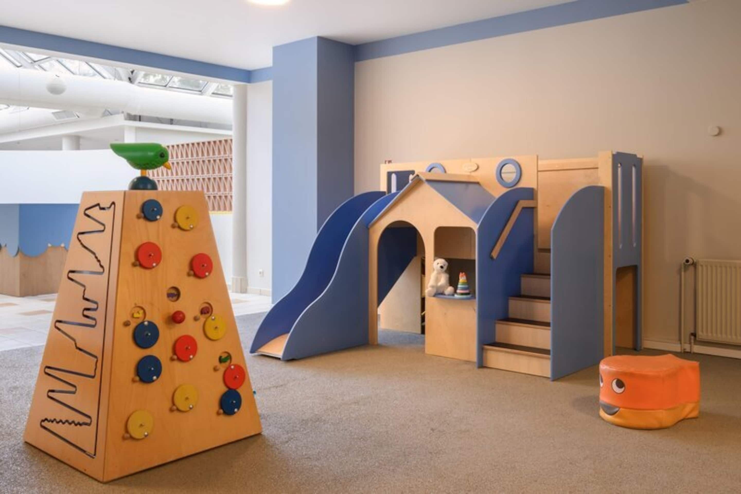 A play area with a climbing structure, slide, and small house.