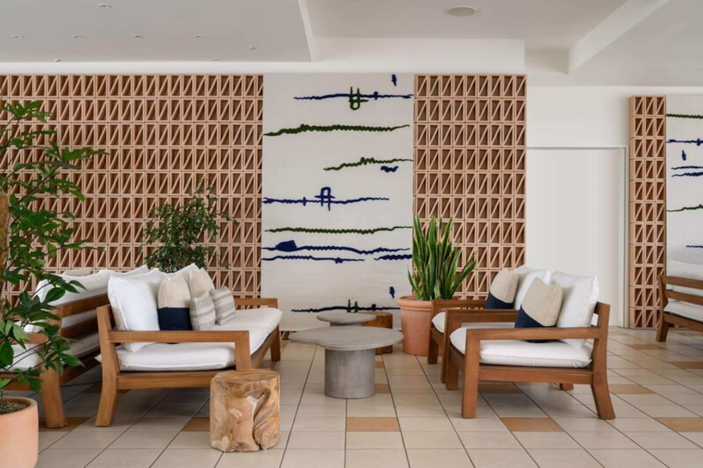 A modern lounge area with wooden furniture, a central round table, and decorative wall panels.