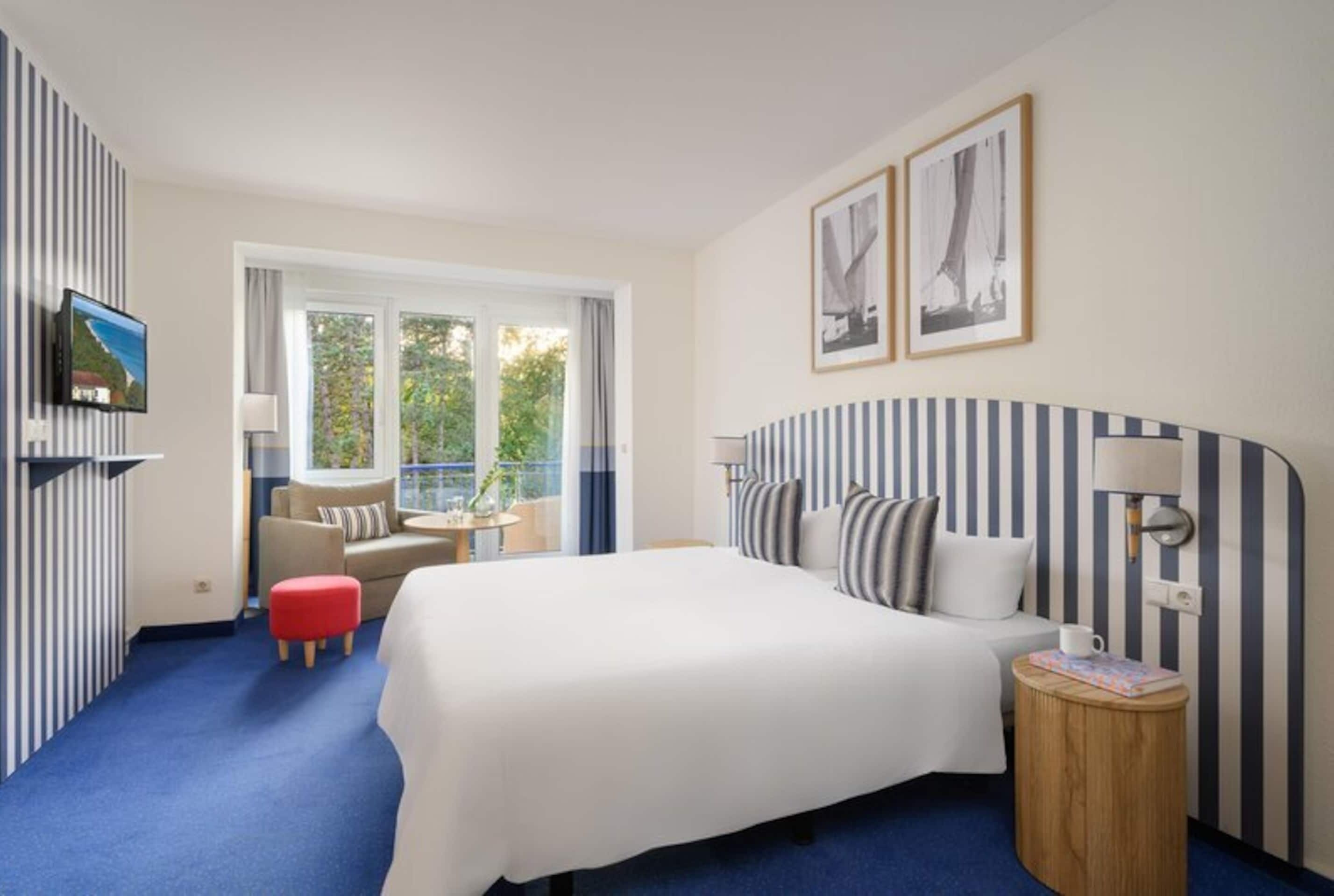 A hotel room with a large bed, a sofa, a small table, and a TV.