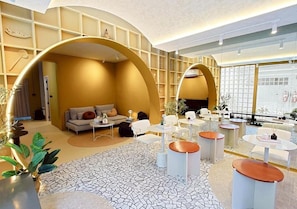 A modern interior with a sofa set, round tables, and a patterned floor. - Au Luna Bangkok Hostel (Bangkok)