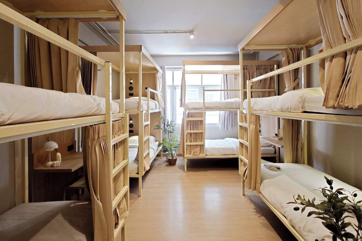 Een slaapkamer met stapelbedden, een bureau, een lamp en een raam met gordijnen.