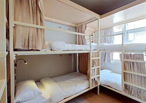 Habitación con literas, ventana, cortinas y lámpara de noche.