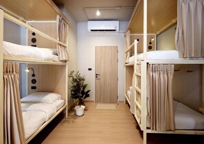 A bunk bed room with a door, a potted plant, and an air conditioning unit. - Au Luna Bangkok Hostel (Bangkok)
