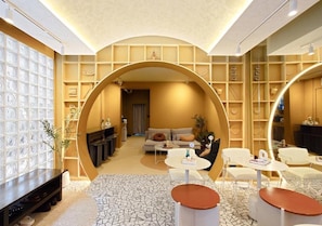A modern interior with a central archway, a seating area with sofas and tables, and a patterned floor. - Au Luna Bangkok Hostel (Bangkok)