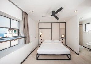 Une chambre à coucher moderne, avec un lit, des tables de chevet et un ventilateur de plafond.