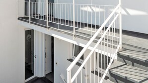 Moderni rakennus, jonka ulkoseinät ovat valkoiset, ja jossa on valkoisilla kaiteilla varustettu parveke sekä kuvioitu katto.
