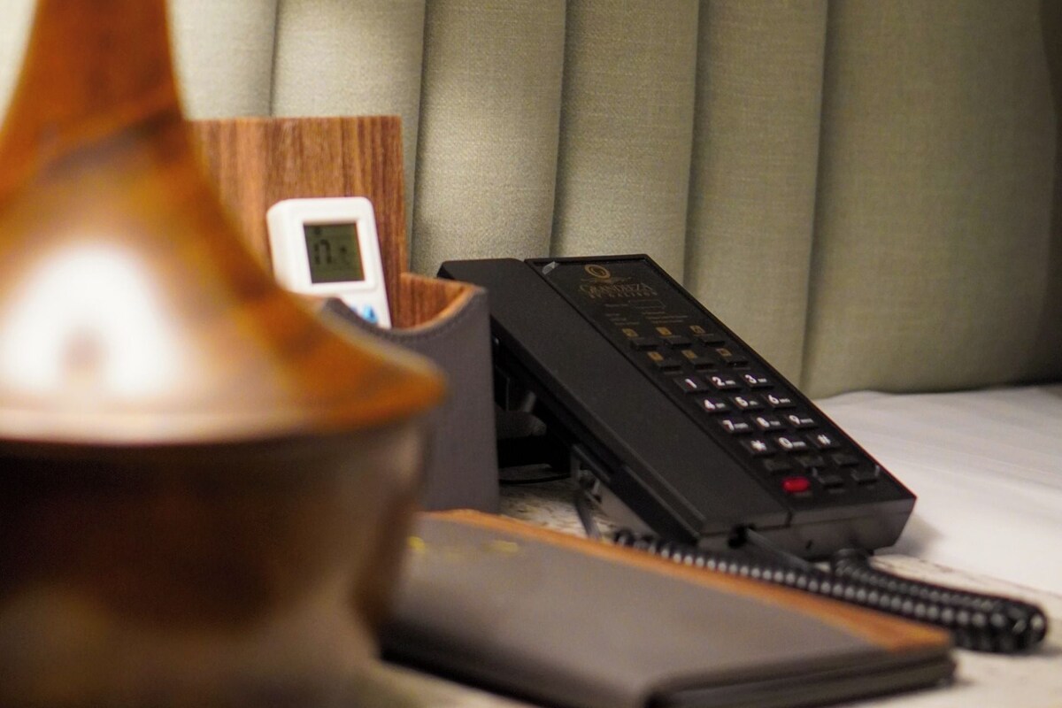 A bedside table with a lamp, a phone, and a notepad.