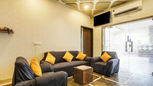 A modern living room with a sofa set, a coffee table, and a large window with a view. - Hotel Johar Inn (Raipur)