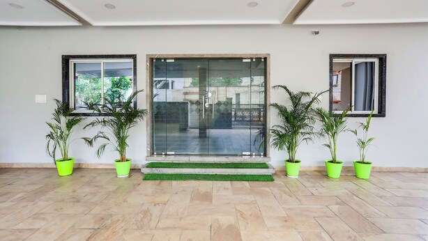 A clean, modern entrance with a glass door, potted plants, and a tiled floor. - Hotel Johar Inn (Raipur)
