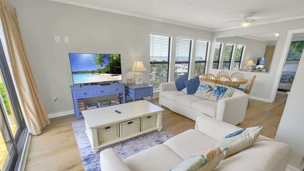 A living room with a television, sofa, and dining area. - 2BR Ocean Bridge - Shore Drive,Pool,Steps to Beach (Myrtle Beach)