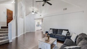 A spacious living room with a gray sofa, a coffee table, and a staircase leading to another level. - Charming 3-Bedroom Home in Prime Frisco Location Fast WiFi & AC (Frisco)