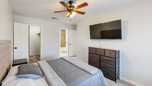 A bedroom with a bed, a dresser, a ceiling fan, and a TV mounted on the wall. - Charming 3-Bedroom Home in Prime Frisco Location Fast WiFi & AC (Frisco)