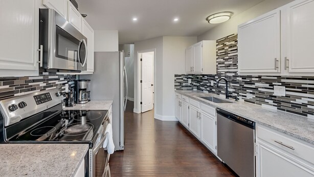 A modern kitchen with white cabinets, a stainless steel microwave, a built-in oven, and a dishwasher. - Charming 3-Bedroom Home in Prime Frisco Location Fast WiFi & AC (Frisco)