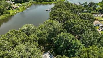 Vista aérea de una zona residencial con un lago, rodeada de abundante vegetación y un puerto deportivo con barcos.