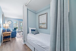 Une chambre à coucher avec un lit, un bureau, une chaise et une fenêtre.
