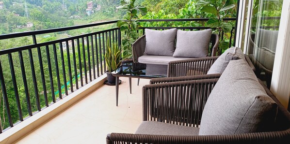 A balcony with wicker furniture, a small table, and a potted plant. - Clarion Hotel De Renees Gangtok ( 5km from MG Marg) (Gangtok)