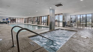 En inomhuspool med bubbelbad, omgiven av glasväggar och med utsikt över omgivningen.