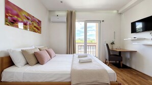 Une chambre d’hôtel équipée d’un lit, d’un bureau, d’une chaise, d’une télévision et d’un balcon avec vue.