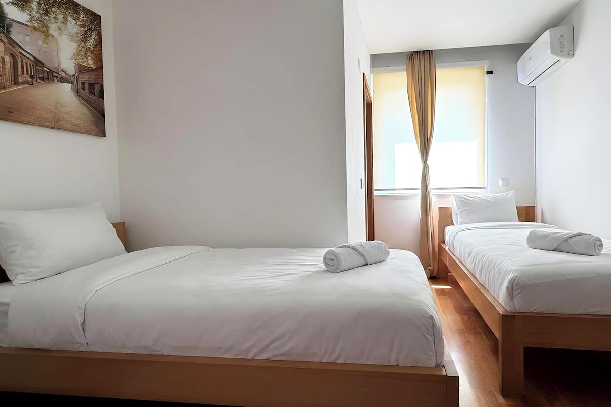 Habitación de hotel con dos camas, un cuadro en la pared y un equipo de aire acondicionado.