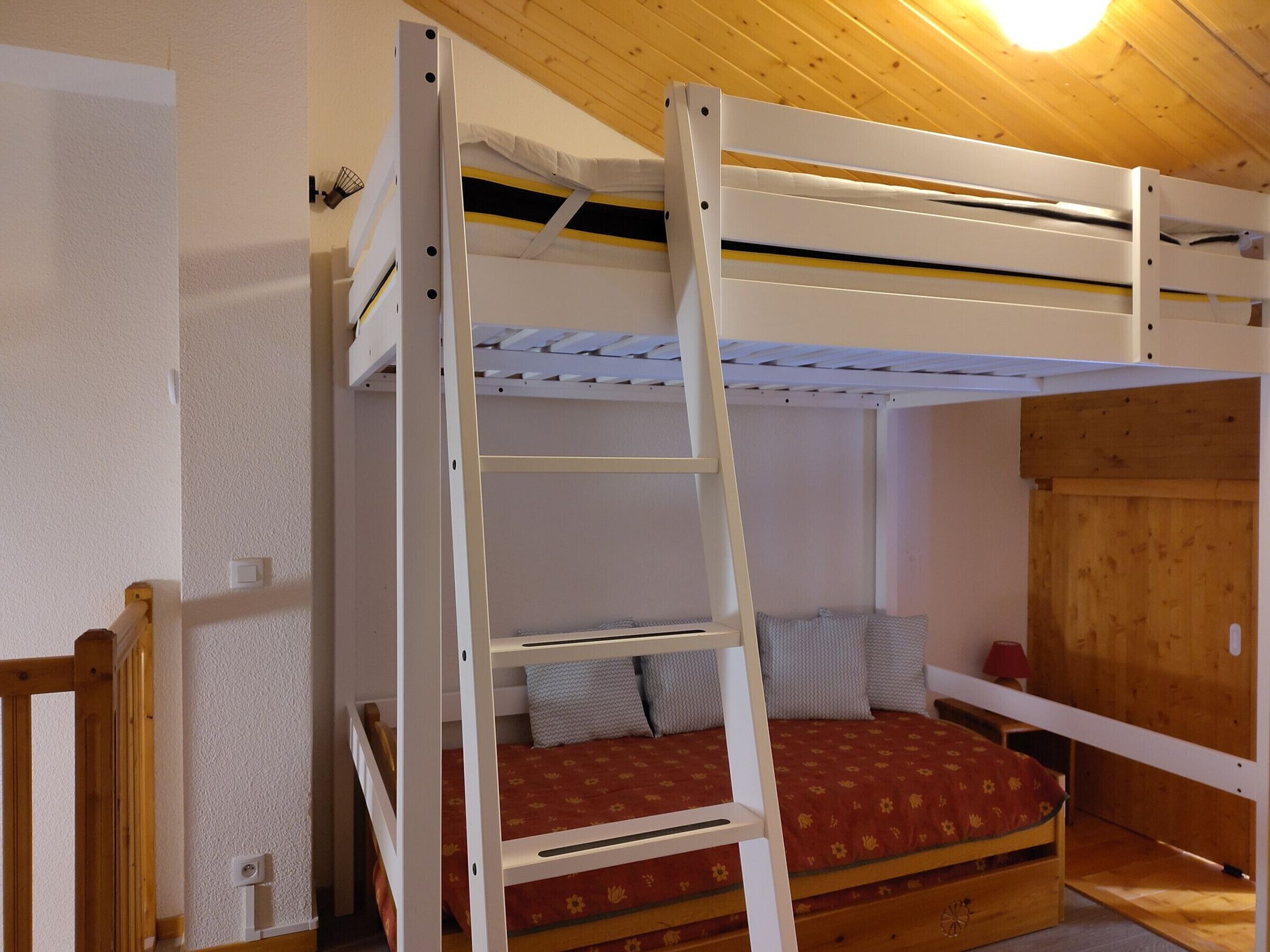 Un lit superposé avec une échelle, des murs en bois et une porte en bois.