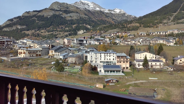 A residential area with modern buildings, a ski slope, and a mountain in the background. - Duplex for 8, Quiet, Near Shuttle and Pool (Aussois)
