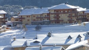 A multi-story hotel with balconies, a snow-covered landscape, and a mountainous backdrop. - Duplex for 8, Quiet, Near Shuttle and Pool (Aussois)